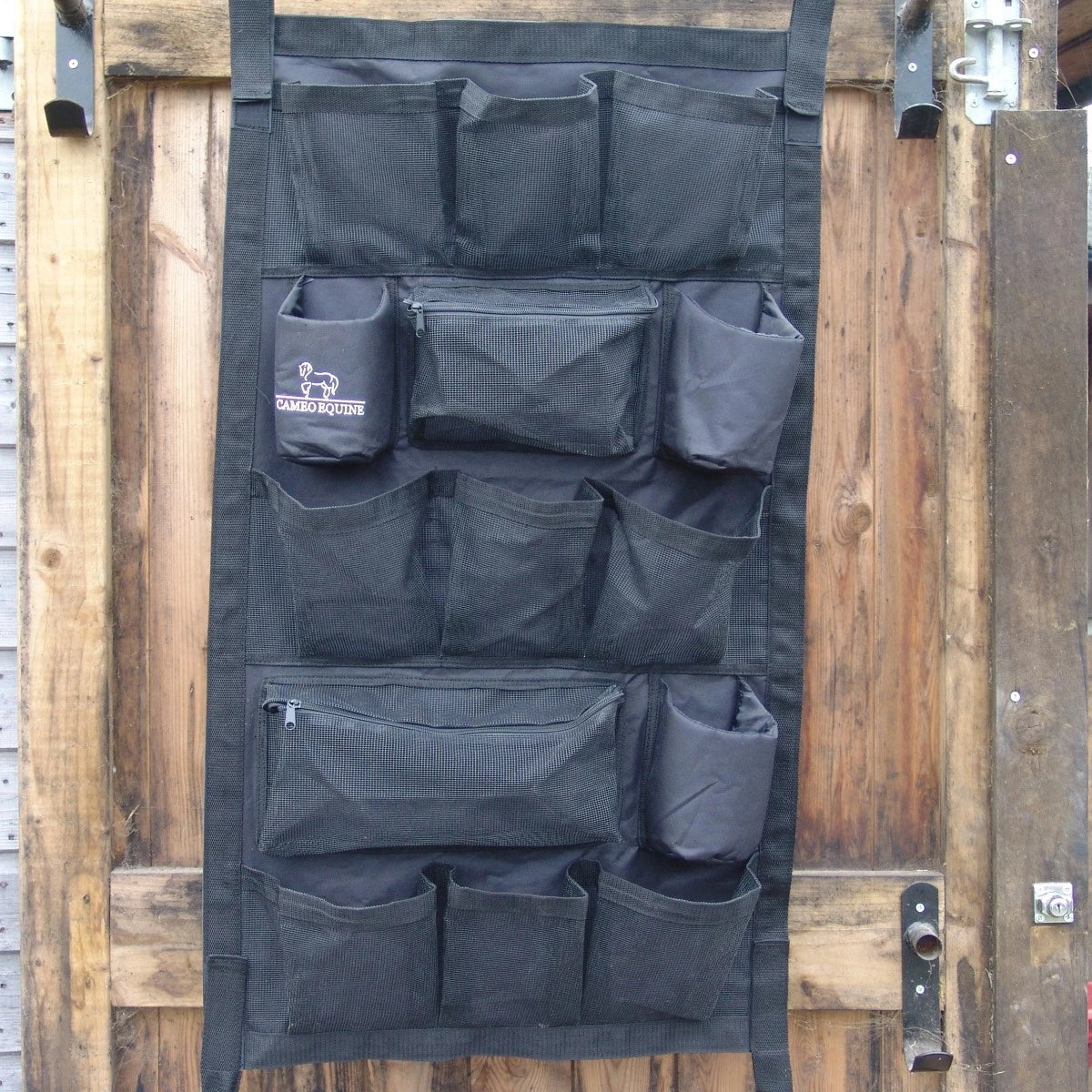 Black wall organizer with multiple pockets on a wooden door