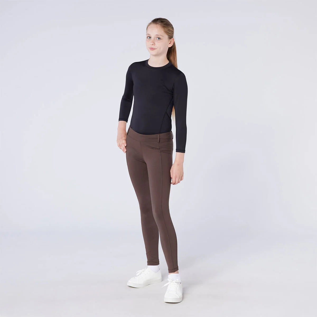CAMEO All Season Riding Tights in Chocolate Brown worn by a junior rider, featuring a high-rise core-supporting waistband and 4-way compression stretch. These technical equestrian leggings include a thermal brushed lining and full-seat silicone chevron grip for security and comfort in the UK.
