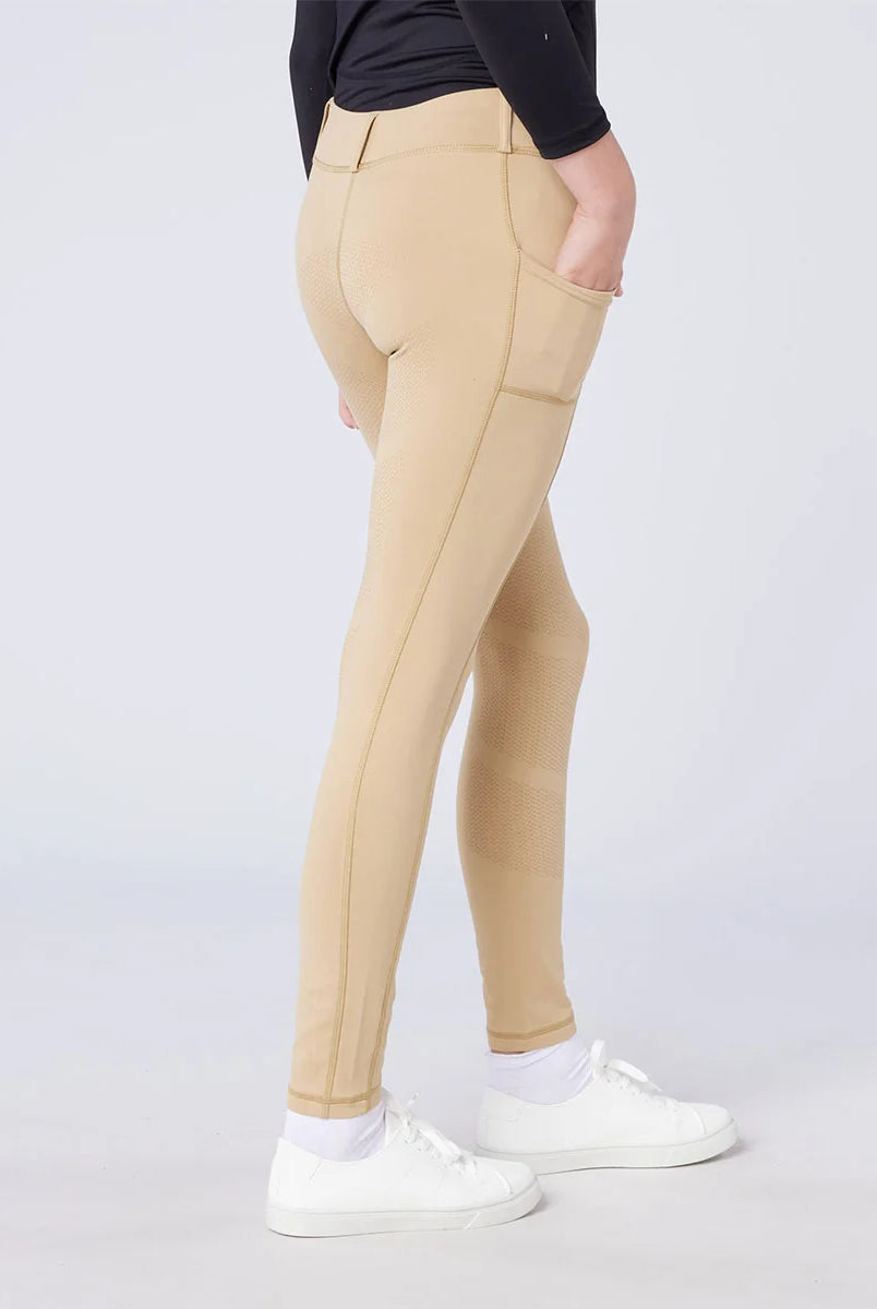 CAMEO All Season Riding Tights in Beige worn by a junior rider, featuring a deep ergonomic thigh smartphone pocket and a full-seat chevron silicone grip for superior in-saddle stability. These technical equestrian leggings include a thermal brushed lining and 4-way compression stretch for UK riders.