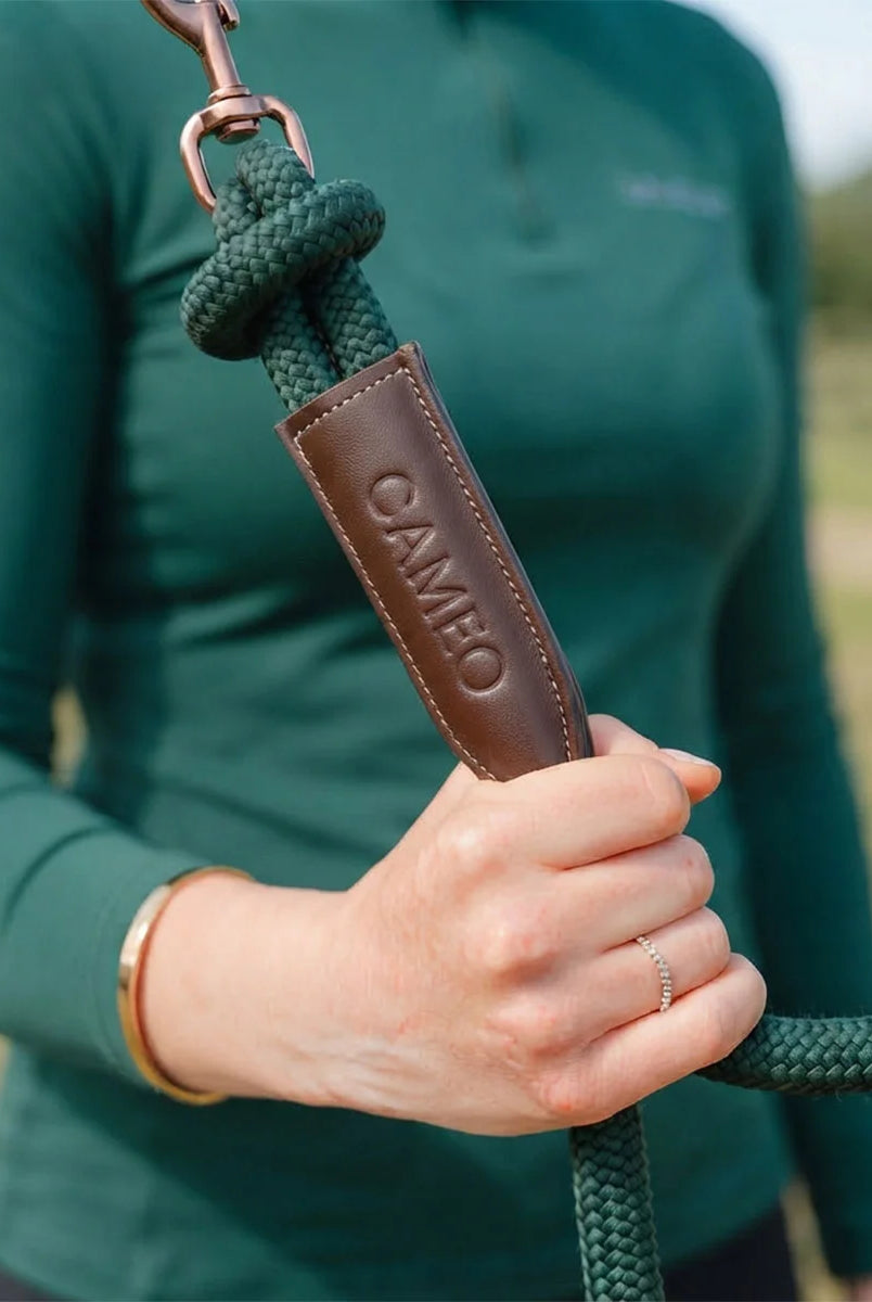 CAMEO Competition Leather Leadrope in EverGreen held by a handler, showcasing the thick braided rope, debossed brown leather branding sleeve, and swivel trigger clip engineered for burn-free grip and refined control during leading and ringside handling.