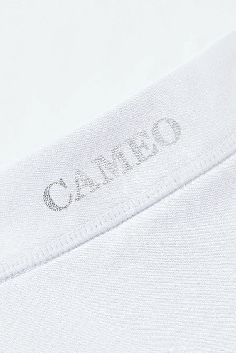 CAMEO Core Collection Baselayer in White showcasing a macro view of the reflective silver CAMEO logo and premium anti-chafing flat-lock seams. This technical detail highlights the breathable CameoTech 4-way stretch fabric engineered for professional equestrian competition and training comfort.