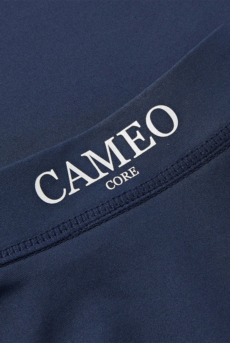CAMEO Junior Core Baselayer in Navy showing a macro close-up of the crisp CAMEO CORE branding and premium anti-chafing flat-lock seams. The high-performance CameoTech 4-way stretch fabric is visible, highlighting the technical microfibre construction used for youth equestrian training and comfort.