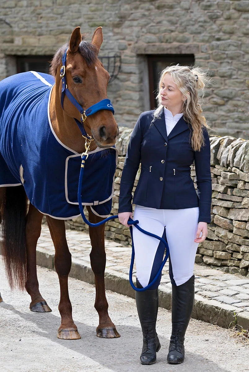 CAMEO Suede Elite Headcollar & Rope set in Navy worn by a chestnut horse alongside a rider in competition wear, showcasing the padded micro-suede noseband, brass fittings, and matching twisted leadrope engineered for nasal pressure dispersal, anti-rub comfort, and luxury showground presentation.