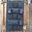 Black wall organizer with multiple pockets on a wooden door
