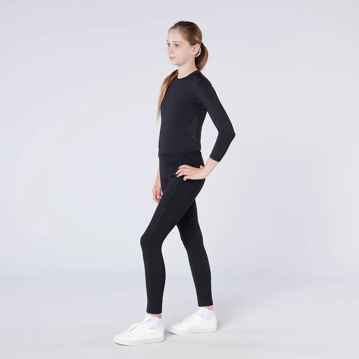 CAMEO All Season Riding Tights in Black worn by a junior rider featuring an innovative full-seat silicone chevron grip and high-rise core-supporting waistband. These technical equestrian leggings provide thermal brushed microfibre warmth and 4-way compression stretch for all-weather riding in the UK.