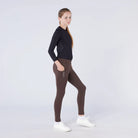CAMEO All Season Riding Tights in Chocolate Brown worn by a junior rider, featuring a deep ergonomic thigh smartphone pocket with CAMEO branding. These technical equestrian leggings provide thermal brushed lining, 4-way compression stretch, and a full-seat silicone grip for all-weather riding in the UK.