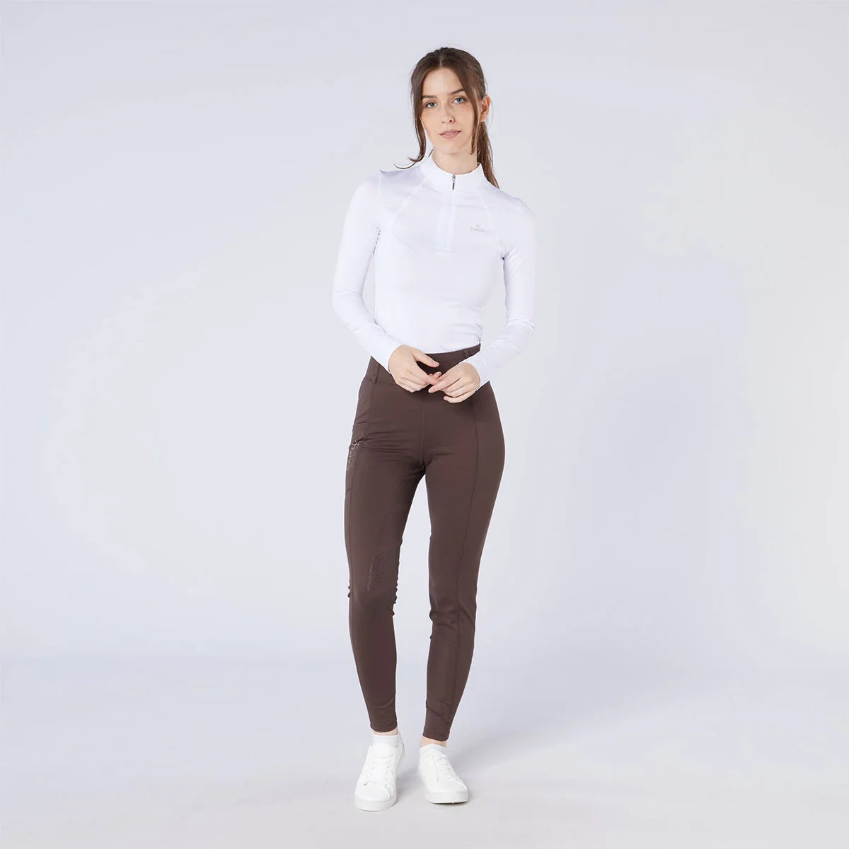 CAMEO All Season Tights in Chocolate Brown worn by a rider featuring a high-rise core-supporting waistband and 4-way compression stretch. These technical equestrian riding tights include an innovative full-seat silicone chevron grip and thermal brushed lining for all-weather training in the UK.