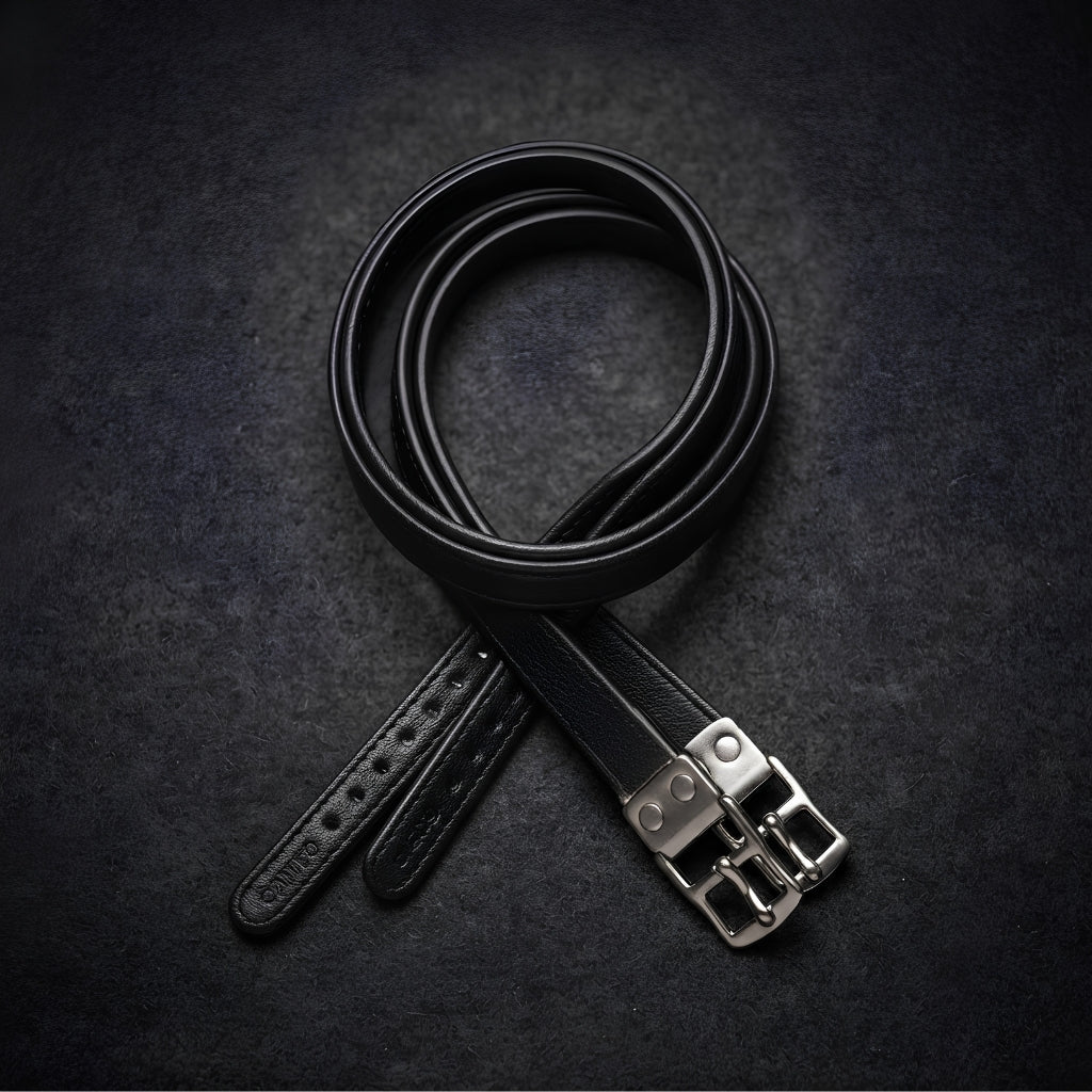 A black leather wrapped competition calfskin stirrup leather coiled on a dark textured background, featuring a silver-toned metal buckle and a visible 'Cameo' brand engraving on the strap end.