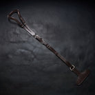 A dark brown leather crupper with T with metal buckles, laid diagonally on a dark textured background.