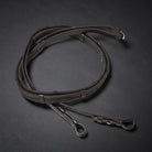 A black rubber grip leather reins, coiled on a dark textured background. with silver metal fittings