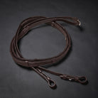 A dark brown leather rubber grip rein with a straight bit loop and a curb bit loop, coiled on a dark textured background.
