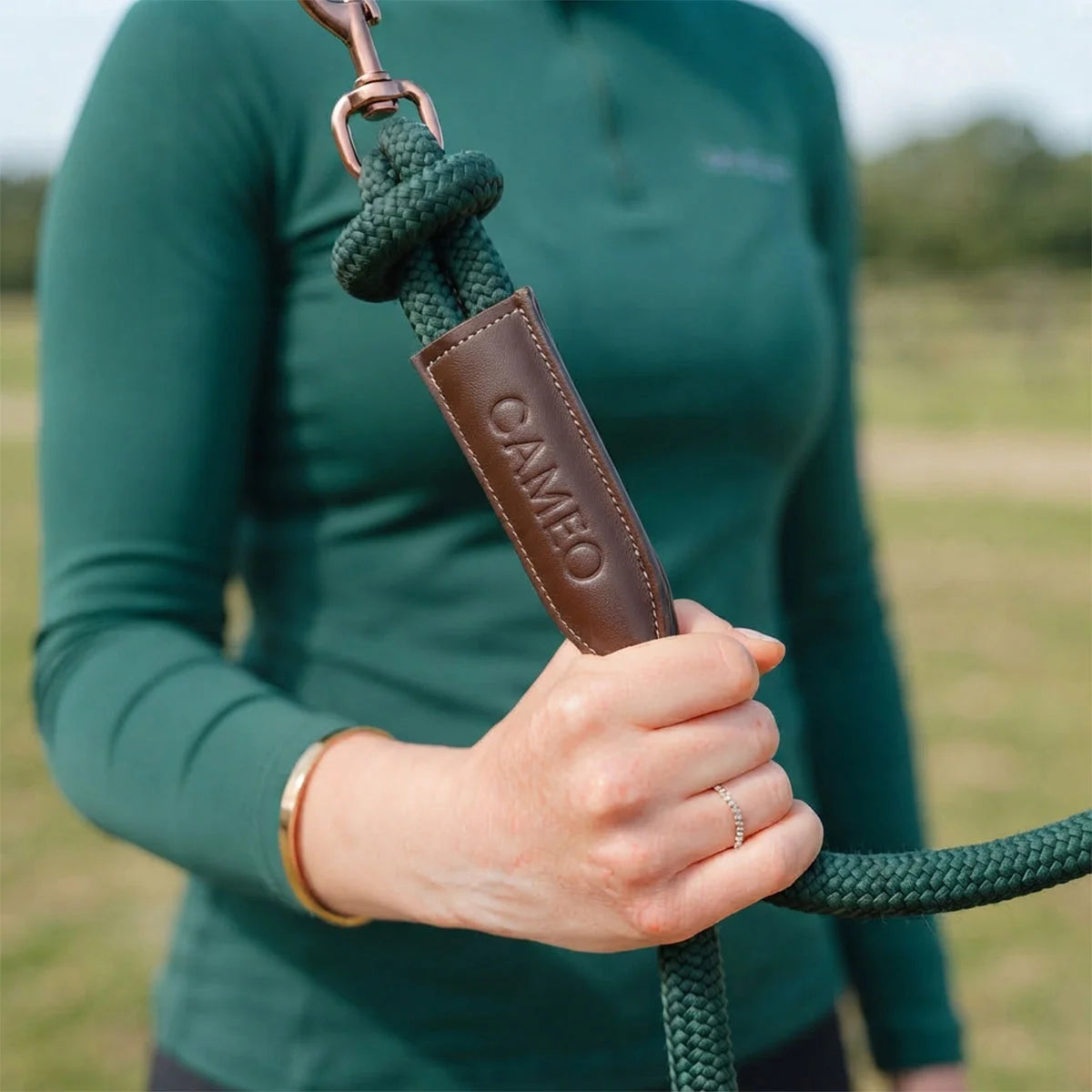 CAMEO Competition Leather Leadrope in EverGreen held by a handler, showcasing the thick braided rope, debossed brown leather branding sleeve, and swivel trigger clip engineered for burn-free grip and refined control during leading and ringside handling.