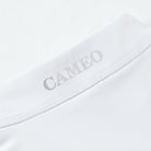 CAMEO Core Collection Baselayer in White showcasing a macro view of the reflective silver CAMEO logo and premium anti-chafing flat-lock seams. This technical detail highlights the breathable CameoTech 4-way stretch fabric engineered for professional equestrian competition and training comfort.