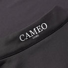 CAMEO Core Collection Baselayer in Black featuring a macro view of the reflective silver CAMEO CORE branding and premium anti-chafing flat-lock seams. The technical 4-way stretch CameoTech microfibre fabric is visible, engineered for active thermoregulation and professional equestrian performance.