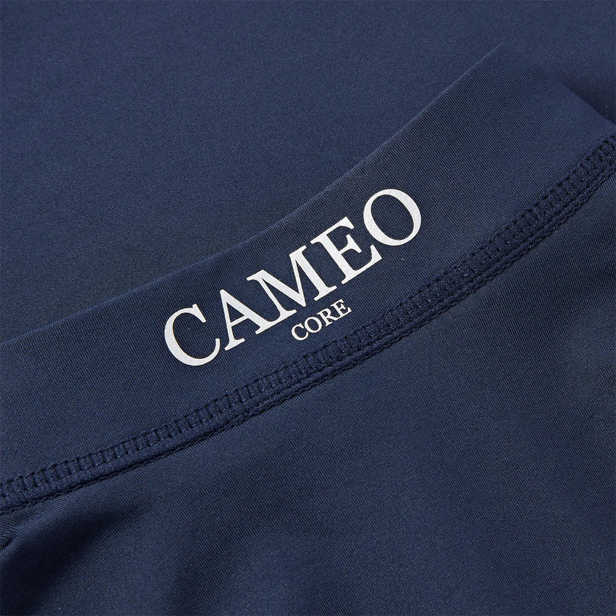 CAMEO Junior Core Baselayer in Navy showing a macro close-up of the crisp CAMEO CORE branding and premium anti-chafing flat-lock seams. The high-performance CameoTech 4-way stretch fabric is visible, highlighting the technical microfibre construction used for youth equestrian training and comfort.