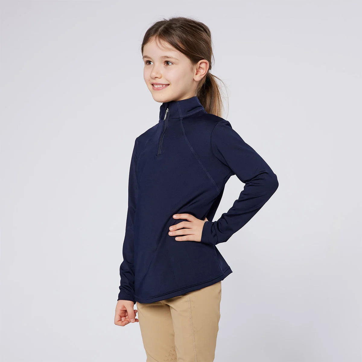 CAMEO Junior Core Baselayer in Navy featuring a high-performance quarter-zip stand collar and ergonomic raglan sleeves. Worn by a young rider, this moisture-wicking equestrian top uses CameoTech 4-way stretch fabric and flat-lock seams to ensure athletic freedom and comfort for Pony Club training.