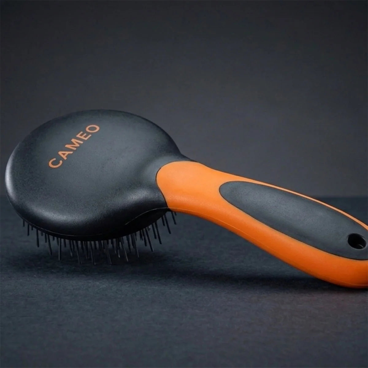 CAMEO Mane & Tail Brush in Orange on a studio background showing the cushioned round paddle head and flexible pins.