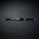 A black leather horse girth with silver metal buckles, displayed horizontally against a dark textured background.