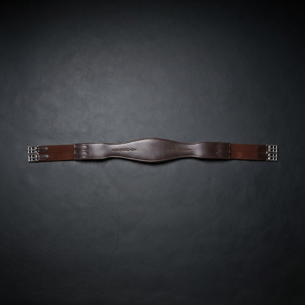 A brown leather horse girth with silver metal buckles, displayed horizontally on a dark textured background.